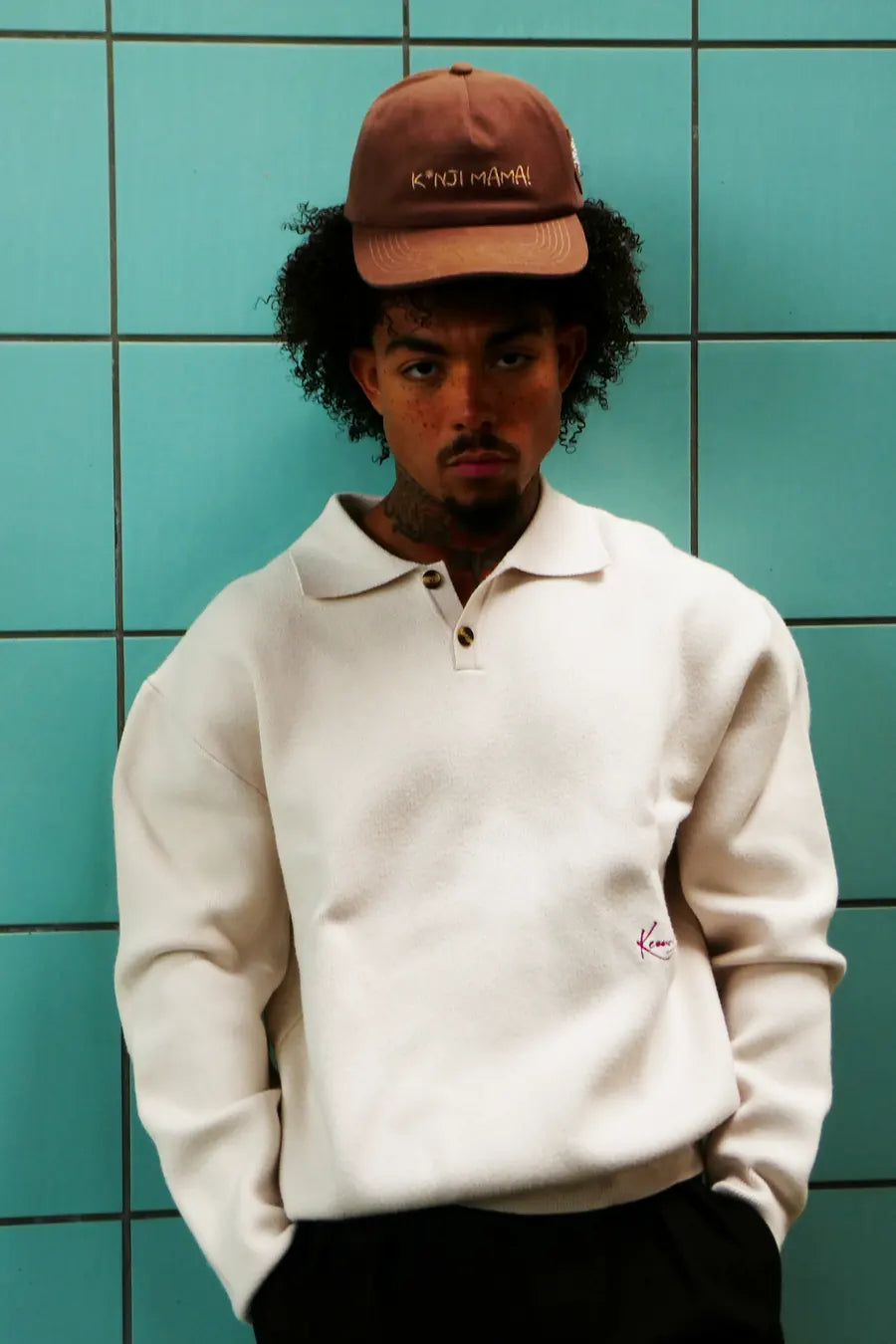 Model in the faded-brown 'K*nji Mama' cap against turquoise tiles