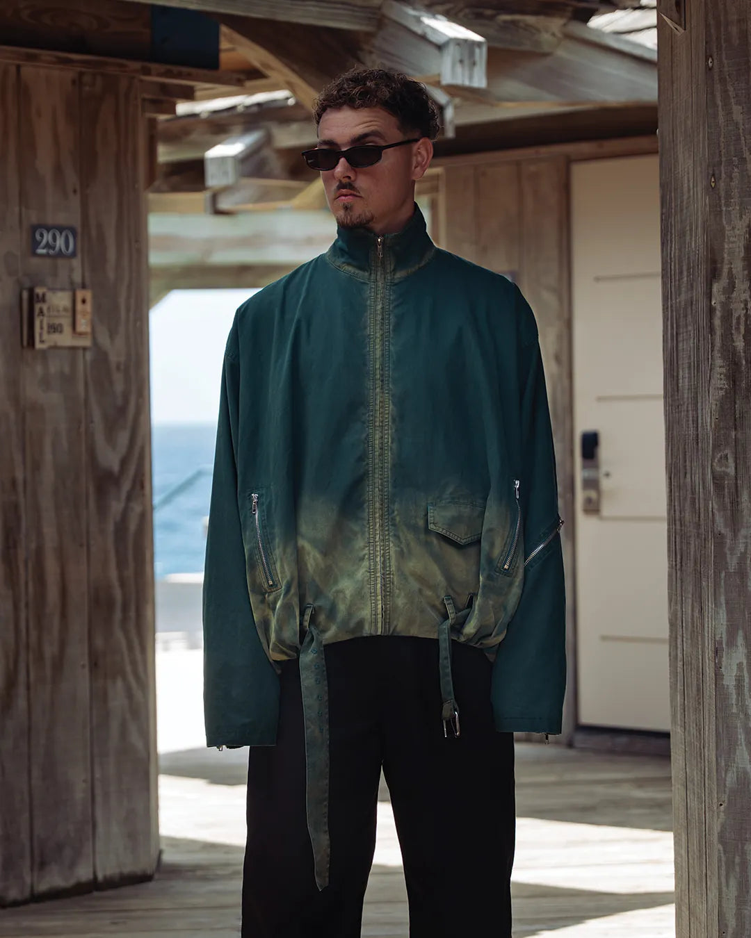 Man in the green hand-washed 'Laman' jacket in a wooden beach house by the sea